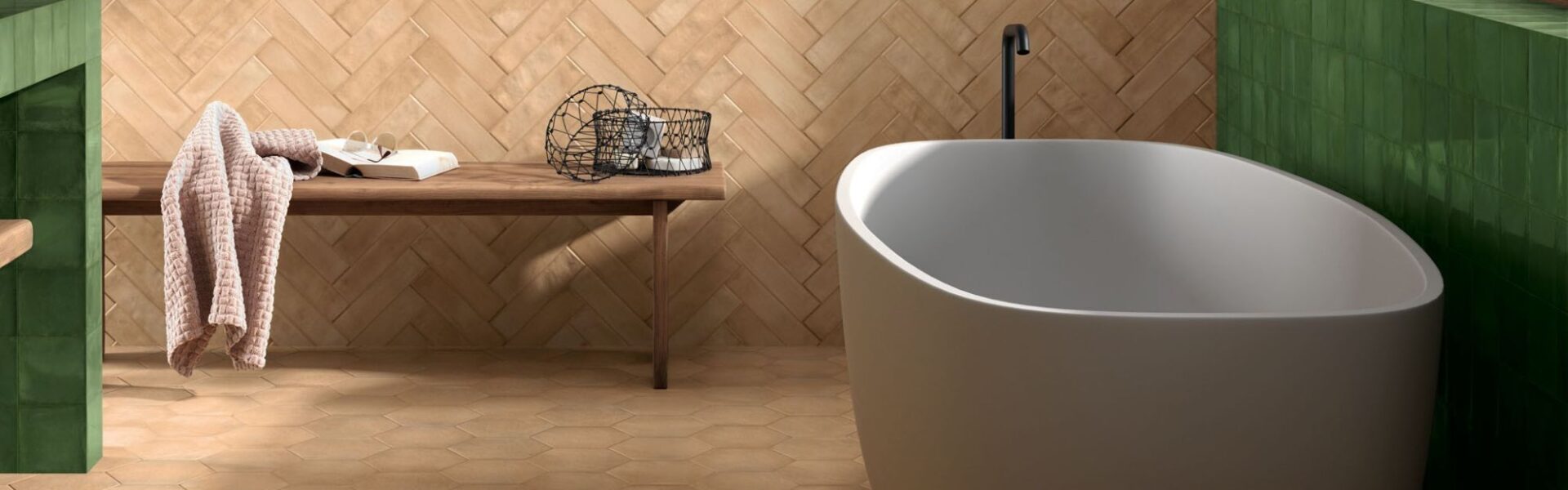 Modern bathroom with a freestanding white tub and a herringbone terracotta tile wall.