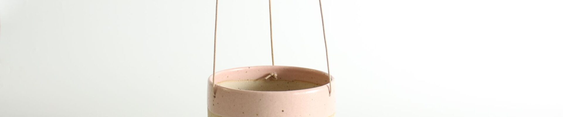 A hanging planter with a pastel pink, cream, and mint green colour block design