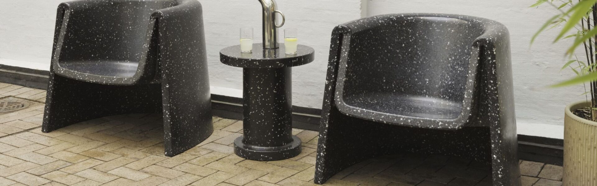 The distinctive cylindrical shape with the speckled texture is characteristic of the Bit series designed by Simon Legald for Normann Copenhagen. You can see two lounge chairs and a smaller side table in the same style.