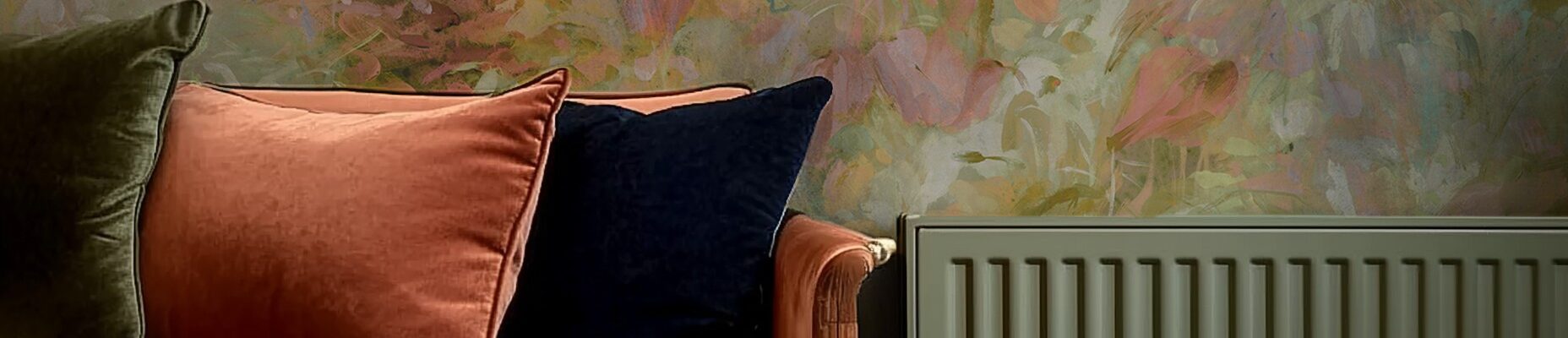 The wallpaper behind the sofa and radiator features a painterly floral design. The colours are soft and muted, with shades of pink, green, and a hint of yellow. The pattern appears abstract, with blurred edges and a watercolour-like quality.