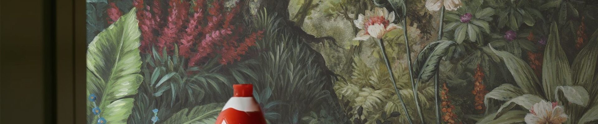 A detailed wallpaper mural depicting a lush, verdant forest scene. A tree trunk dominates the centre, surrounded by a variety of green foliage, red and white flowers.