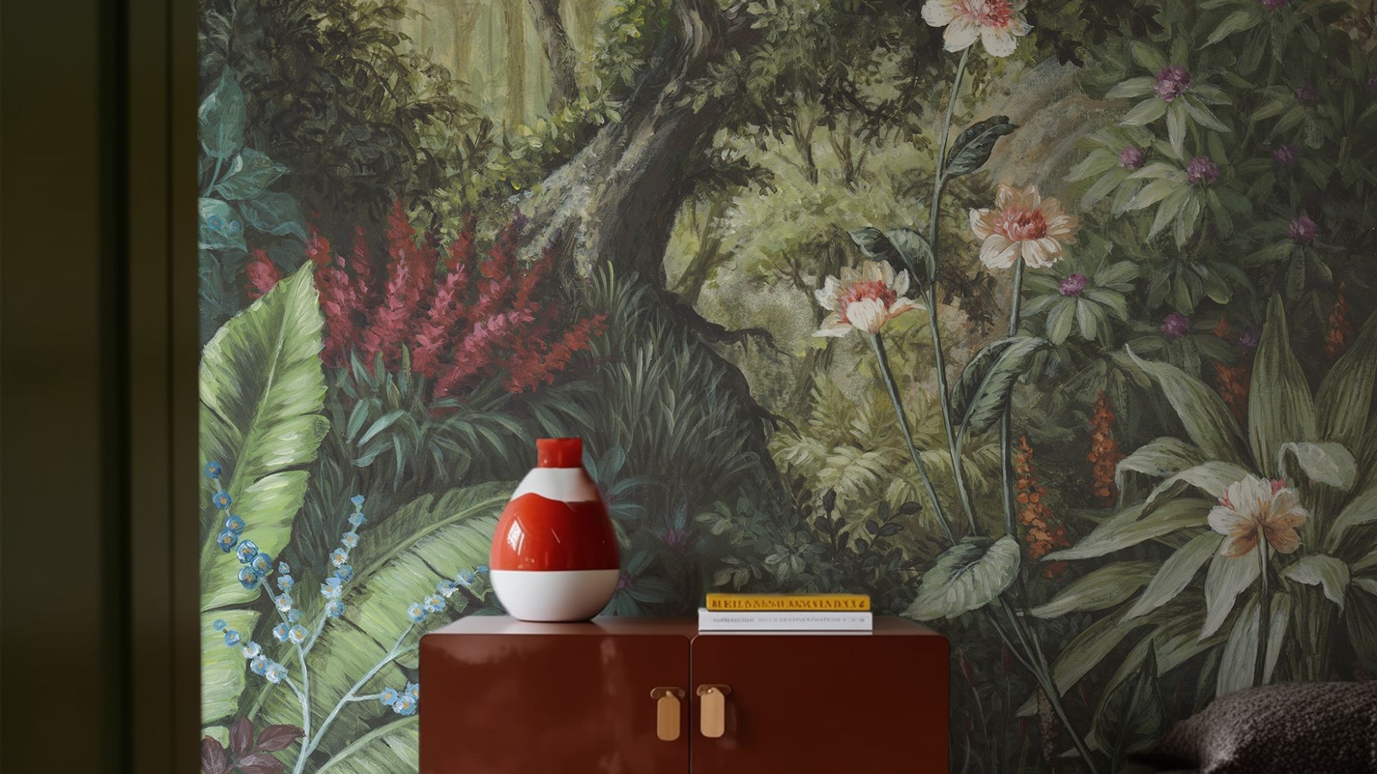 A detailed wallpaper mural depicting a lush, verdant forest scene. A tree trunk dominates the centre, surrounded by a variety of green foliage, red and white flowers.