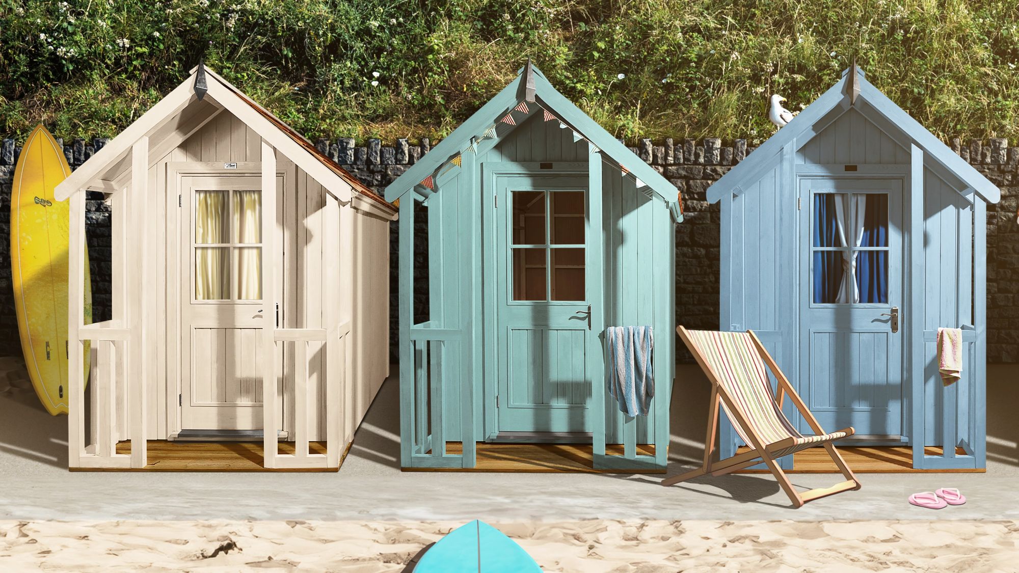 Three colourful beach hut-style sheds on a sandy surface, with surfboards and a beach chair nearby