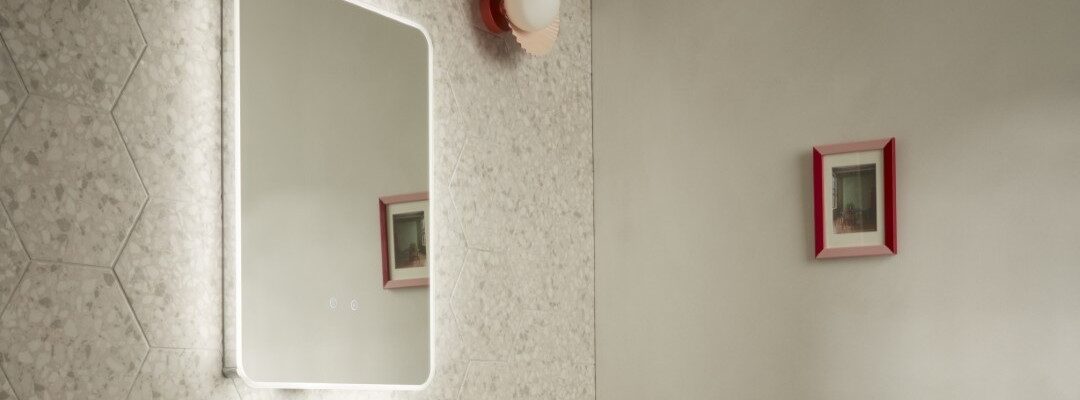 A rectangular mirror with a light glow around the border brings an ethereal feel to bathrooms