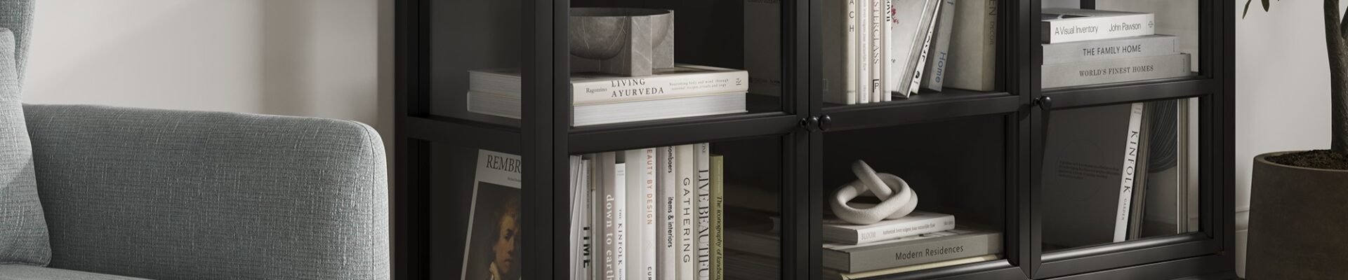 A sleek, modern black sideboard with three glass-fronted doors, each revealing two shelves filled with books and decorative objects.