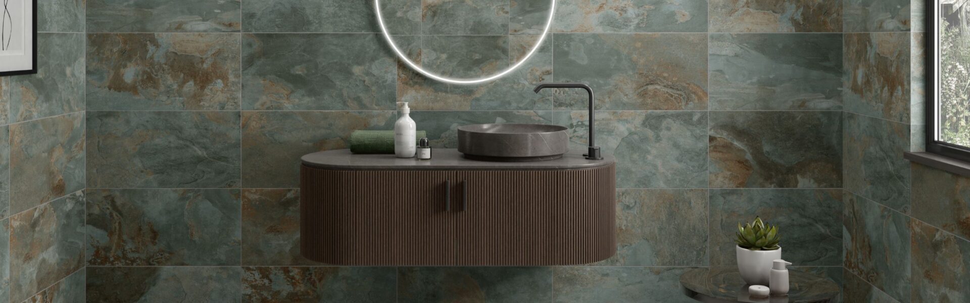 A modern bathroom featuring walls tiled with Strata Green tiles. The tiles have a distressed, multi-tonal appearance with shades of green, brown, and grey.
