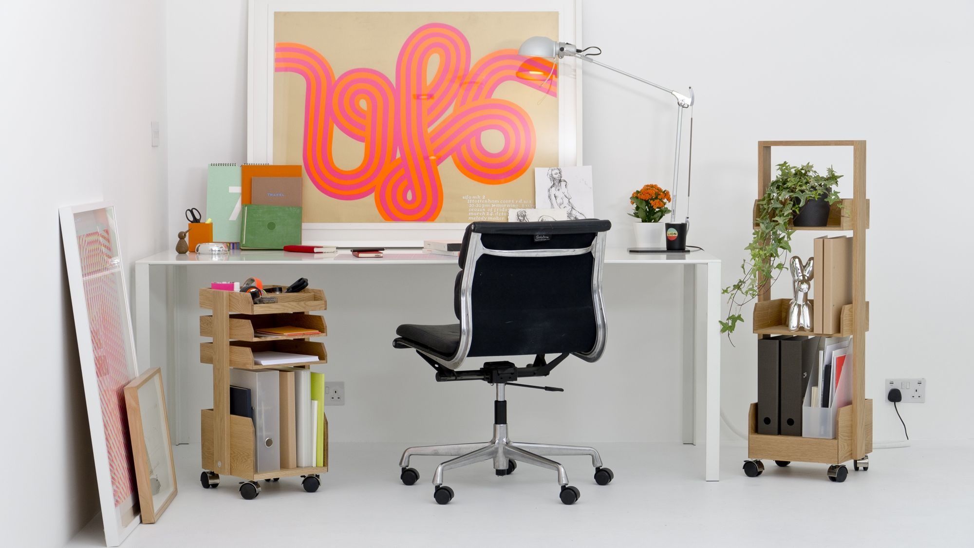 A brightly lit, modern home office space is shown. The room has white walls and a white floor, creating a minimalist backdrop for the furniture.