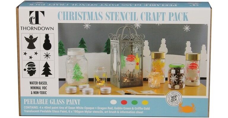 The box displays a wintery scene with a snowy background and various glass jars and lanterns decorated with the provided stencils and paints. The painted items include Santa, a Christmas tree, stars, and snowflakes. A small, unbranded tin of paint is also visible.