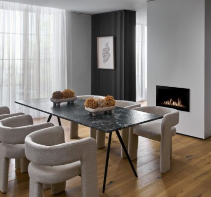 The flooring is a light-coloured wood, arranged in planks, which grounds the space and adds warmth. The room feels sophisticated and modern with a focus on clean lines, varied textures, and a neutral colour palette.