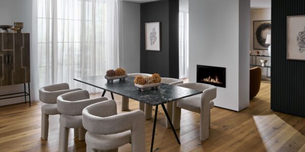 The flooring is a light-coloured wood, arranged in planks, which grounds the space and adds warmth. The room feels sophisticated and modern with a focus on clean lines, varied textures, and a neutral colour palette.