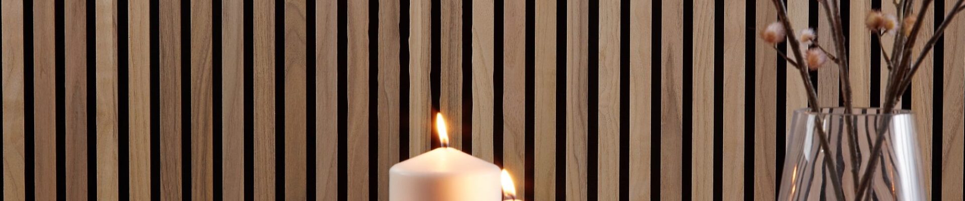 A close-up, horizontal image shows a cosy, homey interior scene. The background is a wall covered with vertical wooden slats in a warm, walnut tone.