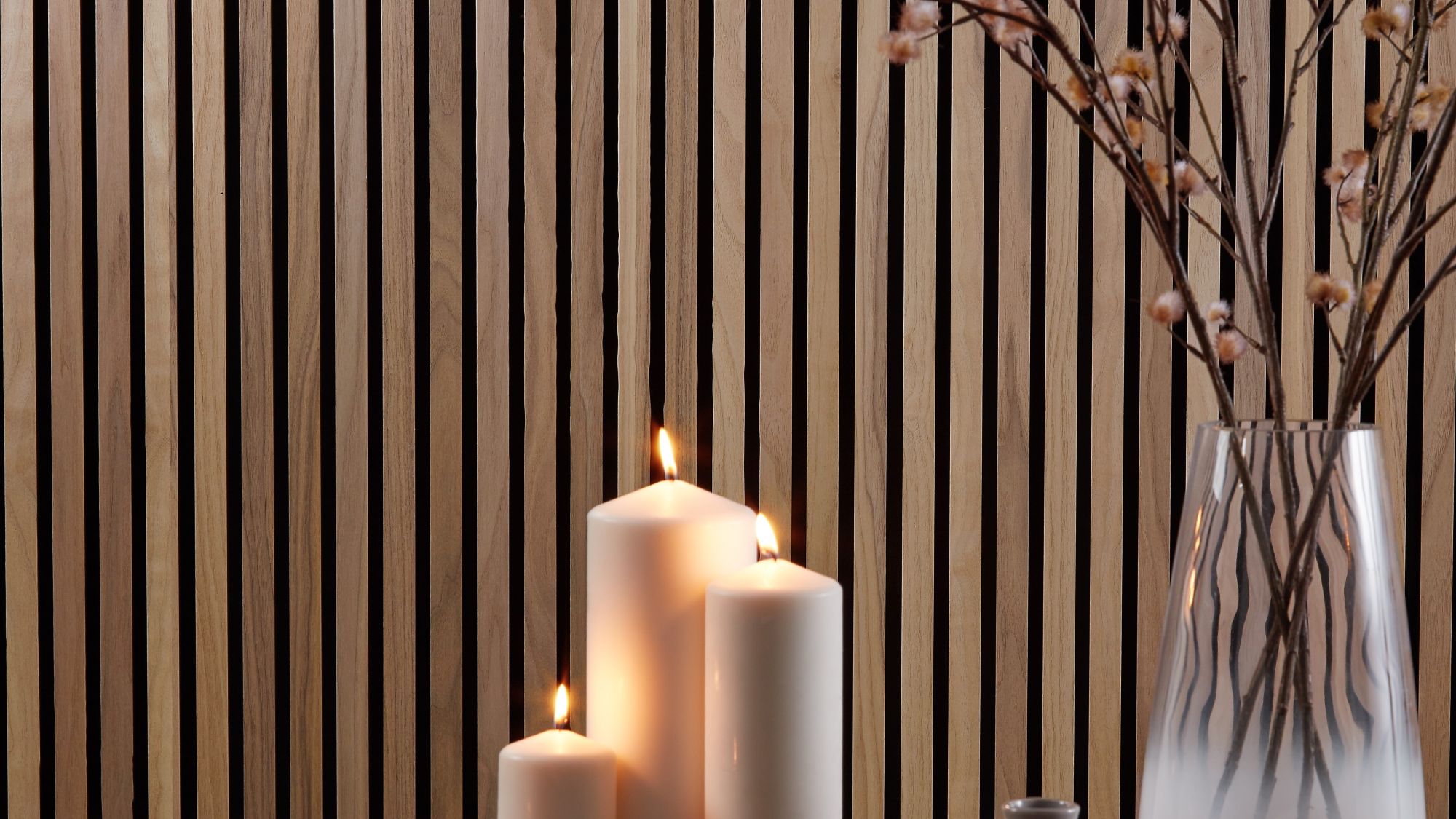 A close-up, horizontal image shows a cosy, homey interior scene. The background is a wall covered with vertical wooden slats in a warm, walnut tone.