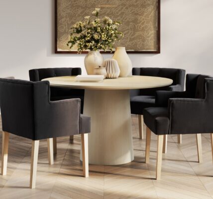 This lifestyle image showcases four Ari-Winged Dining Armchairs in anthracite, a dark gray colour, surrounding a light wood dining table. The chairs feature a clean, contemporary design with a winged backrest that curves slightly around the sides. They are upholstered in a linen blend fabric and rest on light wood legs, which complement the table.