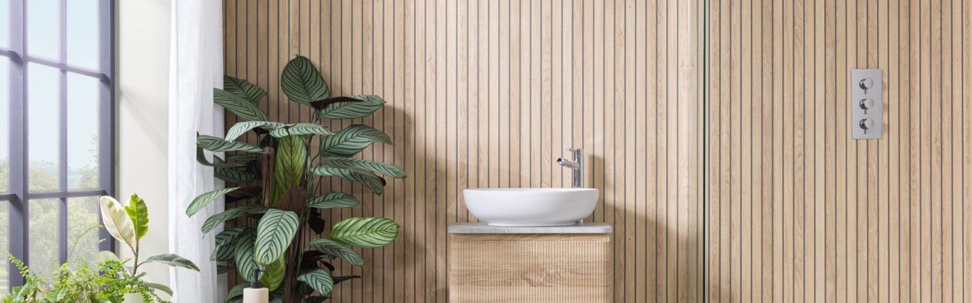 Image shows a bathroom with light wood wall panels laid vertically in a slatted effect.