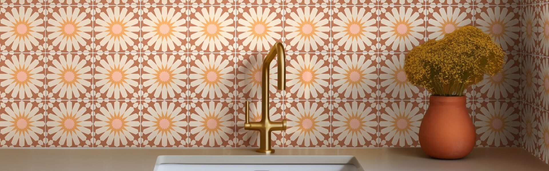 The backsplash is covered in ceramic tiles with a repeating floral pattern. The tiles are a warm terracotta colour with a large, stylized daisy design in the centre of each one. The daisy petals are a light cream or off-white, and the centres are a soft pink.