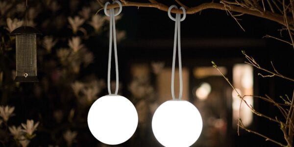 An illuminated spherical outdoor light hung from a tree branch