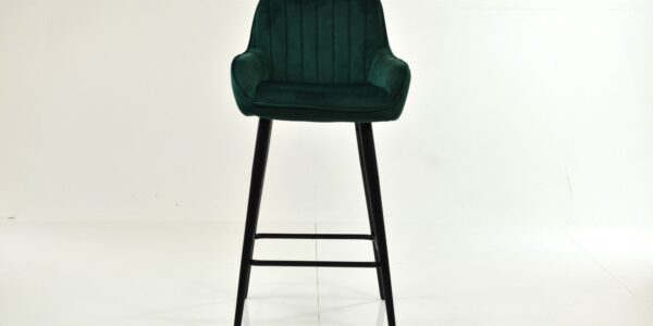 A single, modern bar stool with a deep green, vertically channel-tufted velvet seat and backrest, resting on tall, slim black wooden legs.