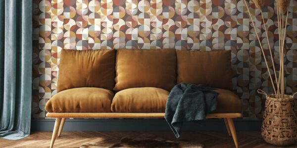 A living room with a three-seater sofa, wooden parquet flooring and denim blue curtains. The background features a geometric wallpaper in different shades of brown, orange and amber