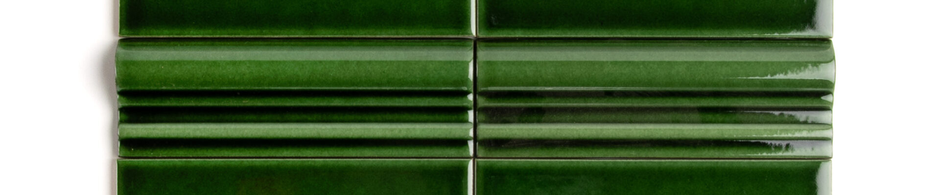 A rich, dark, emerald green tile with a high-gloss finish and dado detailing