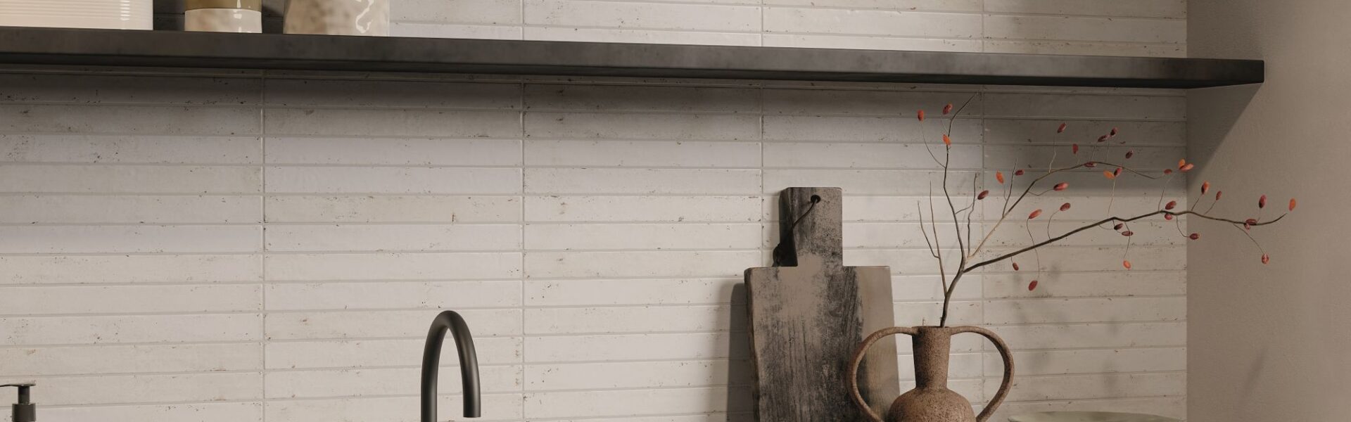 A kitchen splashback with light-coloured, rectangular tiles laid in a horizontal pattern, likely a subway or brick-style layout. The tiles appear to have a handmade or distressed texture with slight variations in colour and surface, giving them an artisan feel. They look like a creamy white or very pale beige/grey.