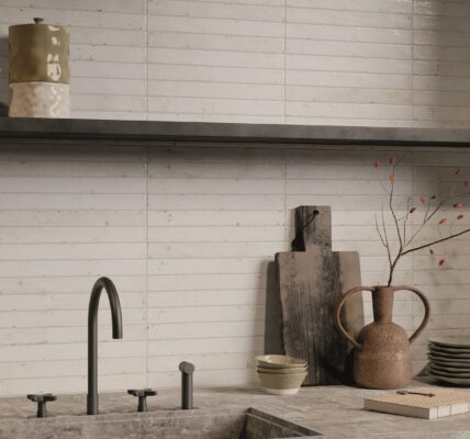 A kitchen splashback with light-coloured, rectangular tiles laid in a horizontal pattern, likely a subway or brick-style layout. The tiles appear to have a handmade or distressed texture with slight variations in colour and surface, giving them an artisan feel. They look like a creamy white or very pale beige/grey.