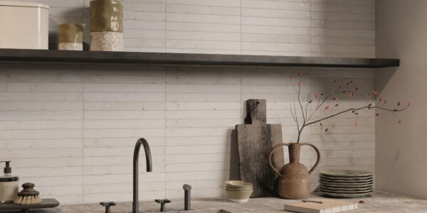 A kitchen splashback with light-coloured, rectangular tiles laid in a horizontal pattern, likely a subway or brick-style layout. The tiles appear to have a handmade or distressed texture with slight variations in colour and surface, giving them an artisan feel. They look like a creamy white or very pale beige/grey.