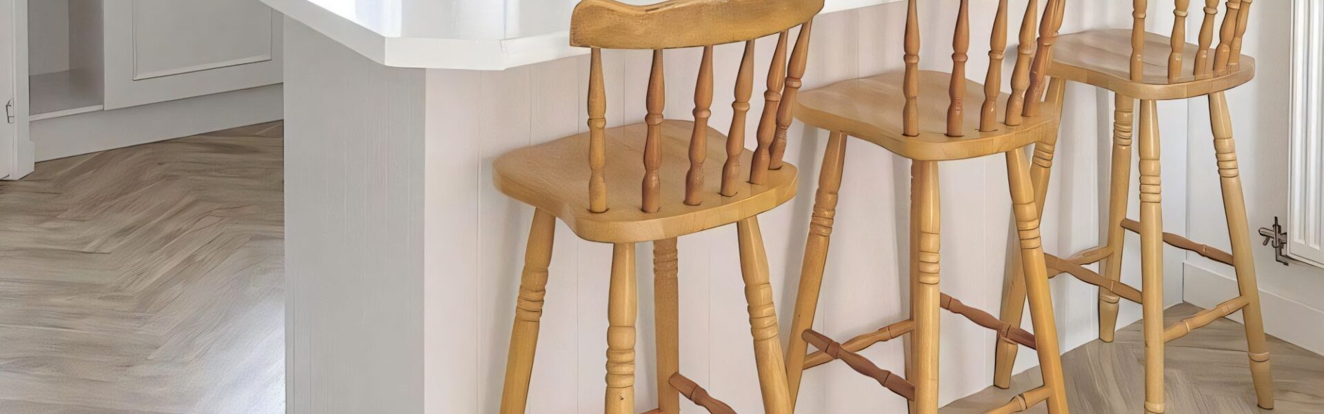 A white kitchen island or breakfast bar with a clean, white countertop. The side facing the viewer appears to be finished with white vertical panelling - possibly V-groove or tongue and groove style.
