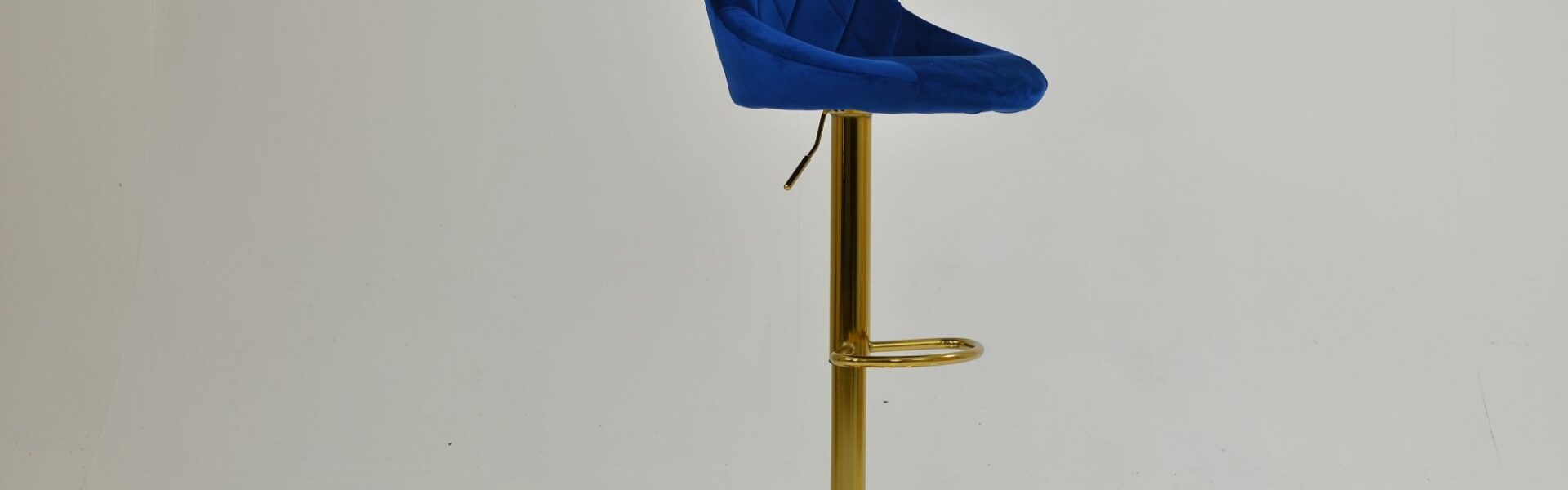 A modern blue velvet bar stool with a diamond-quilted backrest and a polished gold pedestal base.