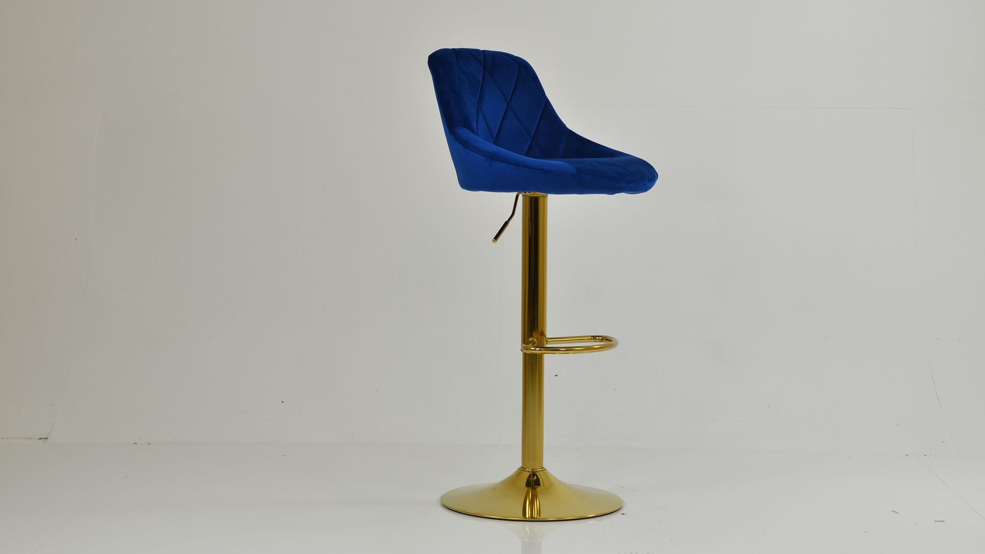 A modern blue velvet bar stool with a diamond-quilted backrest and a polished gold pedestal base.