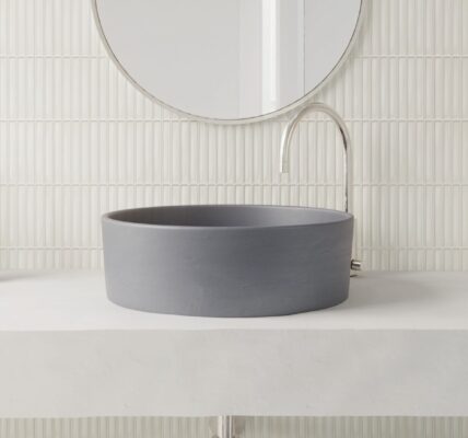 A modern bathroom vanity featuring a matte charcoal vessel sink on a concrete countertop against a white vertical Kit Kat finger tile backsplash.