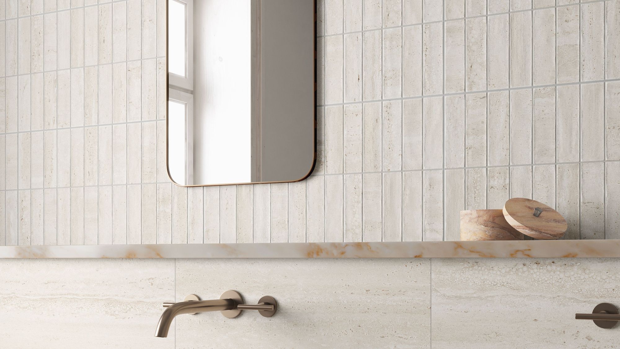 A contemporary bathroom scene featuring light beige, travertine-style wall tiles. The top half of the wall is composed of narrow, vertical kit-kat tiles, while the bottom half consists of large-format horizontal slabs with subtle stone veining.