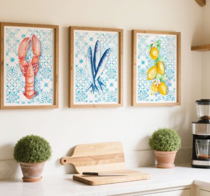 A bright, rustic kitchen featuring a set of three framed Mediterranean-style watercolour prints of a lobster, sardines, and lemons against a blue tiled background