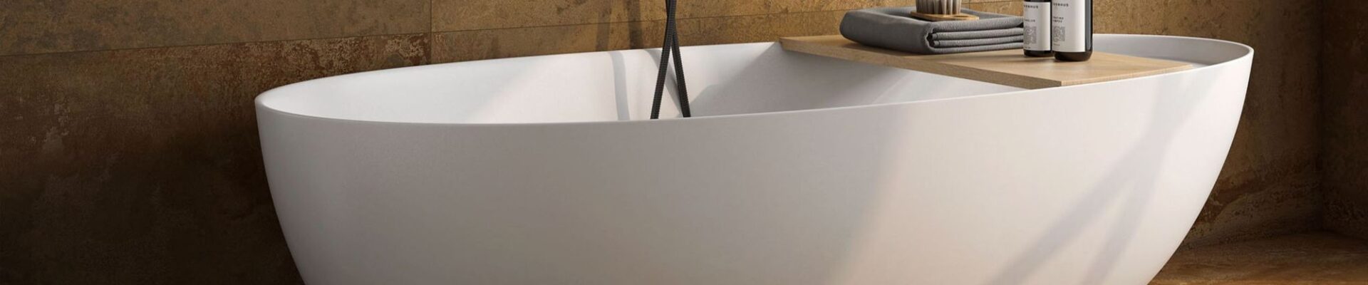 A modern freestanding white oval bathtub set against a backdrop of textured, rustic copper-toned wall and floor tiles.