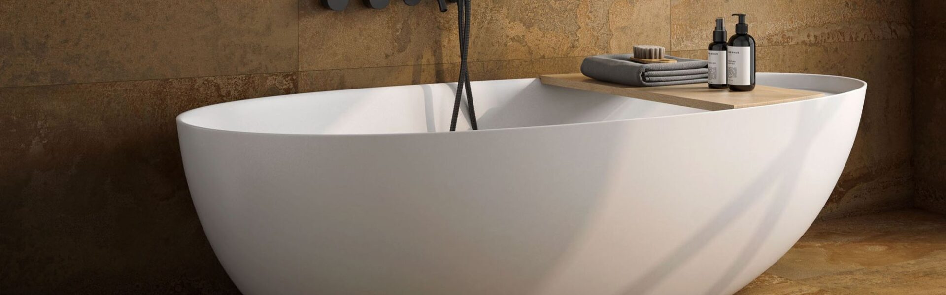 A modern freestanding white oval bathtub set against a backdrop of textured, rustic copper-toned wall and floor tiles.