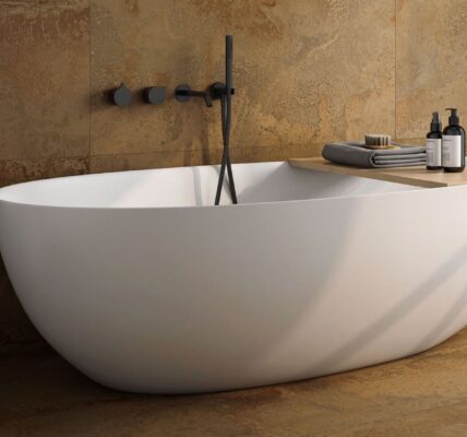 A modern freestanding white oval bathtub set against a backdrop of textured, rustic copper-toned wall and floor tiles.