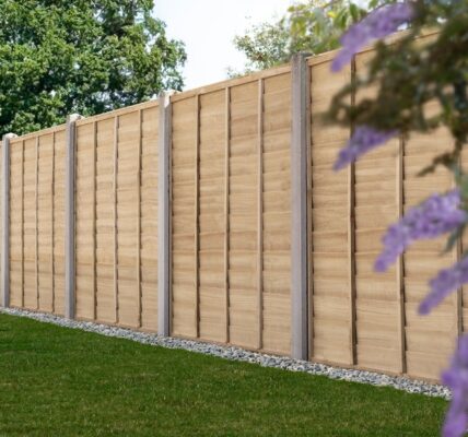 A line of light brown wooden privacy fencing panels is featured, accented by concrete posts that sit at intervals between each section.