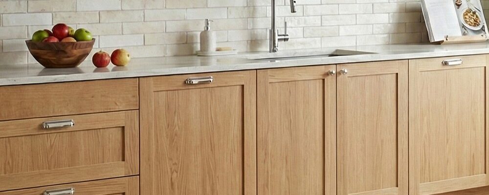 A bright, modern kitchen featuring light-toned solid oak shaker-style cabinets with a natural wood grain finish..