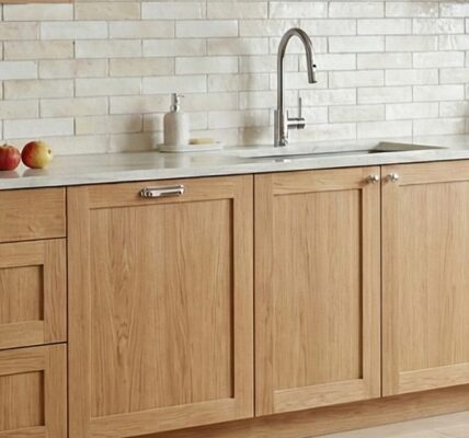 A bright, modern kitchen featuring light-toned solid oak shaker-style cabinets with a natural wood grain finish..