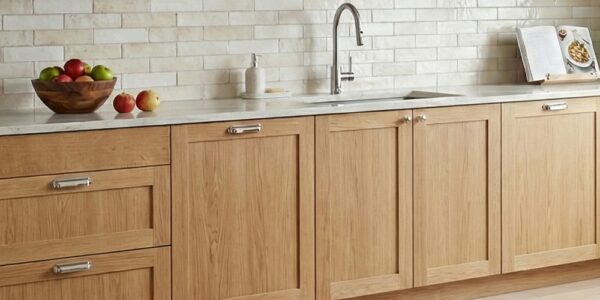 A bright, modern kitchen featuring light-toned solid oak shaker-style cabinets with a natural wood grain finish..