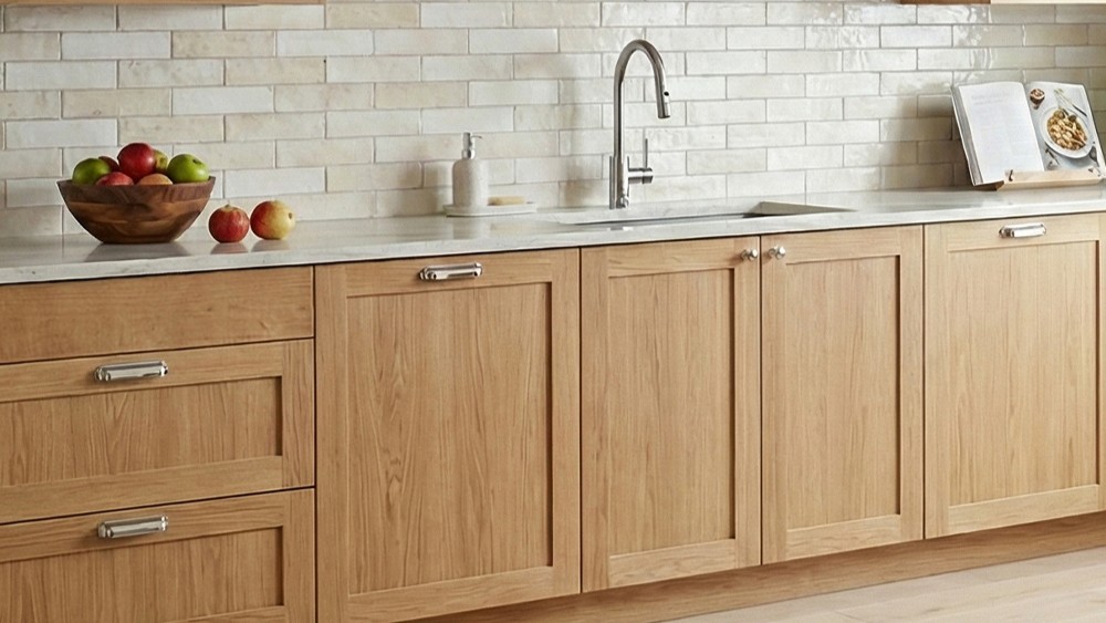 A bright, modern kitchen featuring light-toned solid oak shaker-style cabinets with a natural wood grain finish..