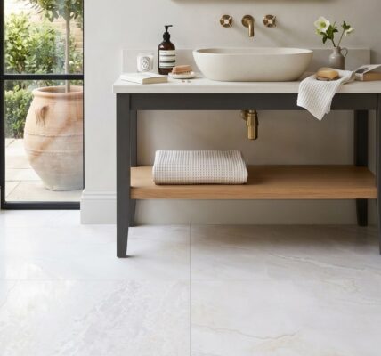 An elegant, brightly lit bathroom interior featuring large, high-gloss white marble floor tiles with subtle grey and gold veining