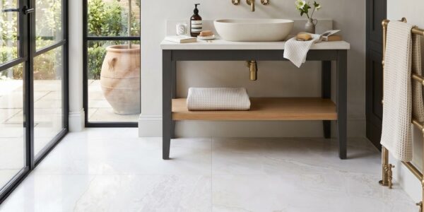 An elegant, brightly lit bathroom interior featuring large, high-gloss white marble floor tiles with subtle grey and gold veining