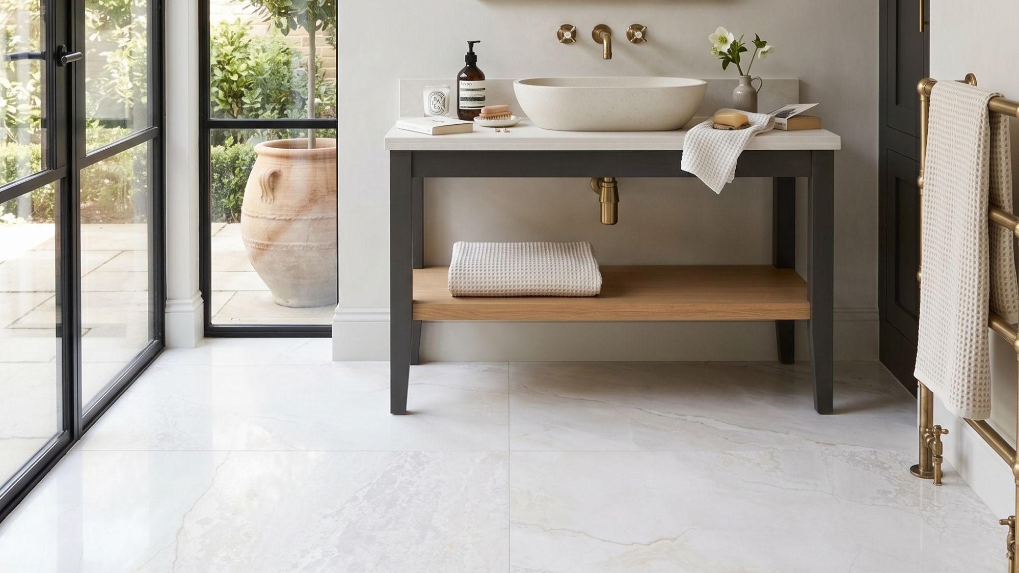 An elegant, brightly lit bathroom interior featuring large, high-gloss white marble floor tiles with subtle grey and gold veining
