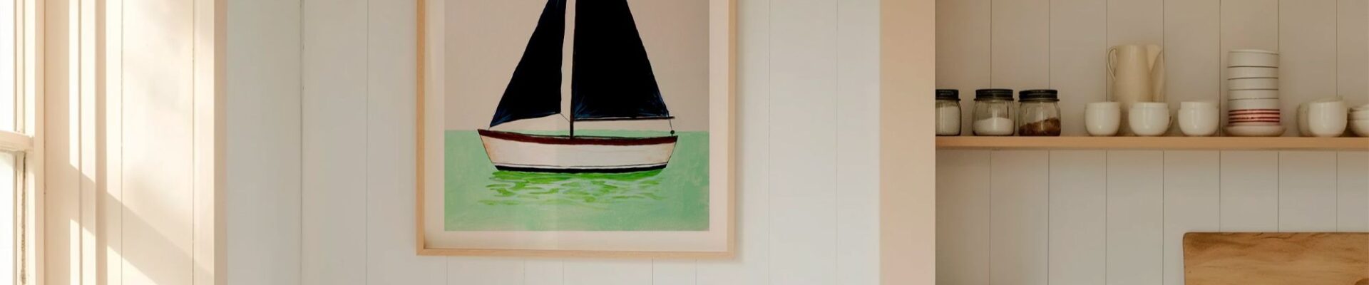 A framed art print of a minimalist sailboat with dark navy blue sails, floating on mint green water against a light beige background. The vertical print is housed in a light wood frame and hangs on a white, vertical-shiplap wall.
