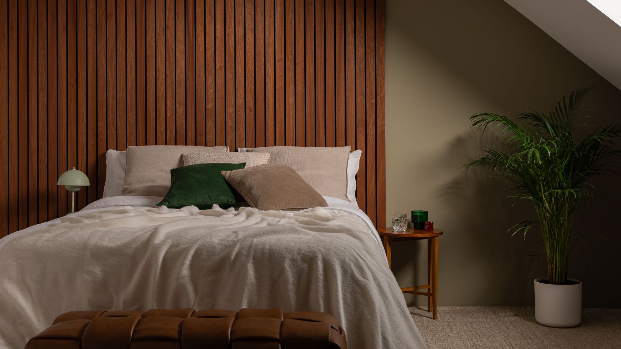 A cosy, modern bedroom featuring a bed with a large, warm-toned Sapele wood slat wall panel serving as a floor-to-ceiling headboard.