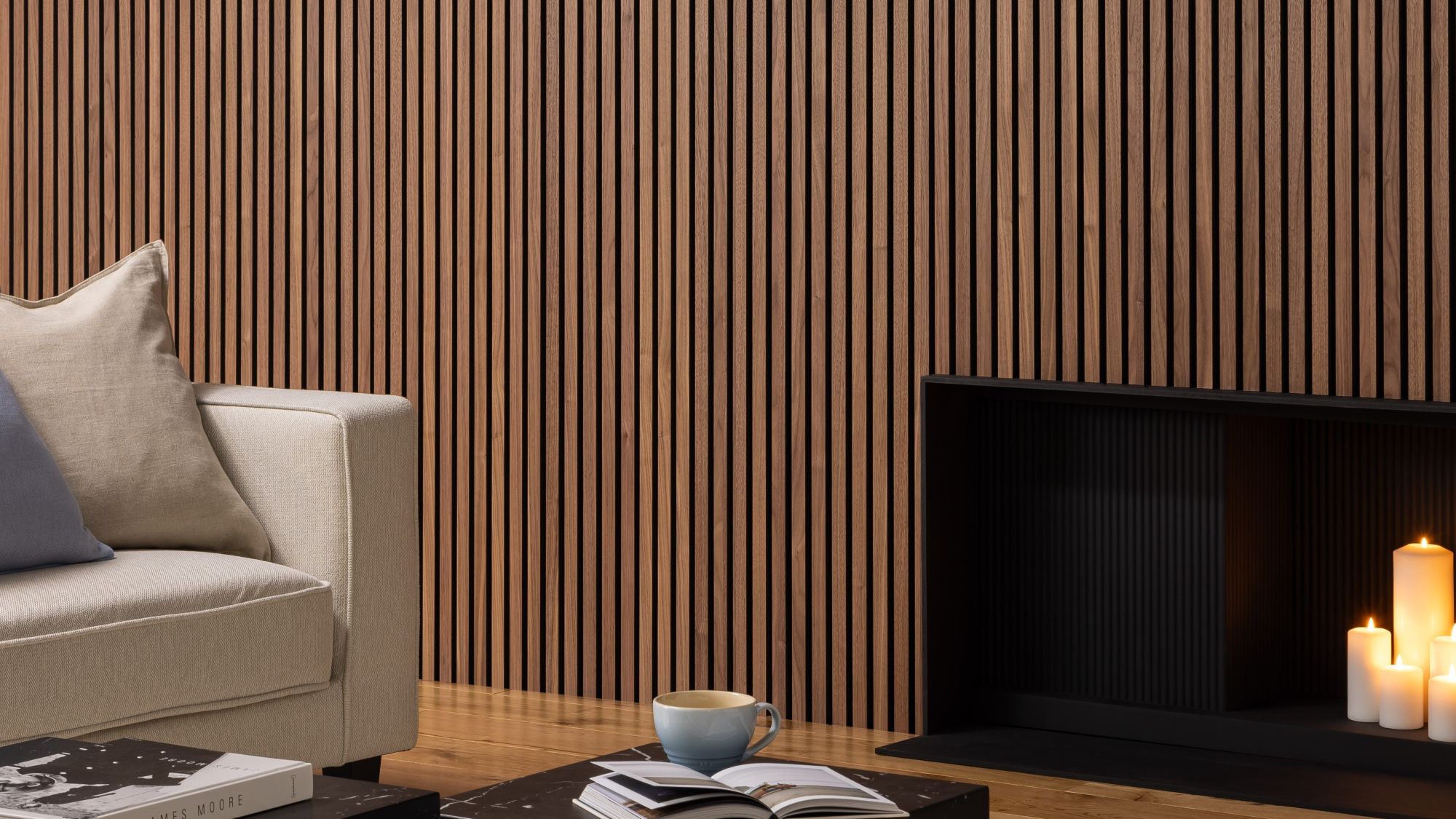 Deep walnut acoustic slatwall panelling mounted on a living room wall behind a sofa and fireplace