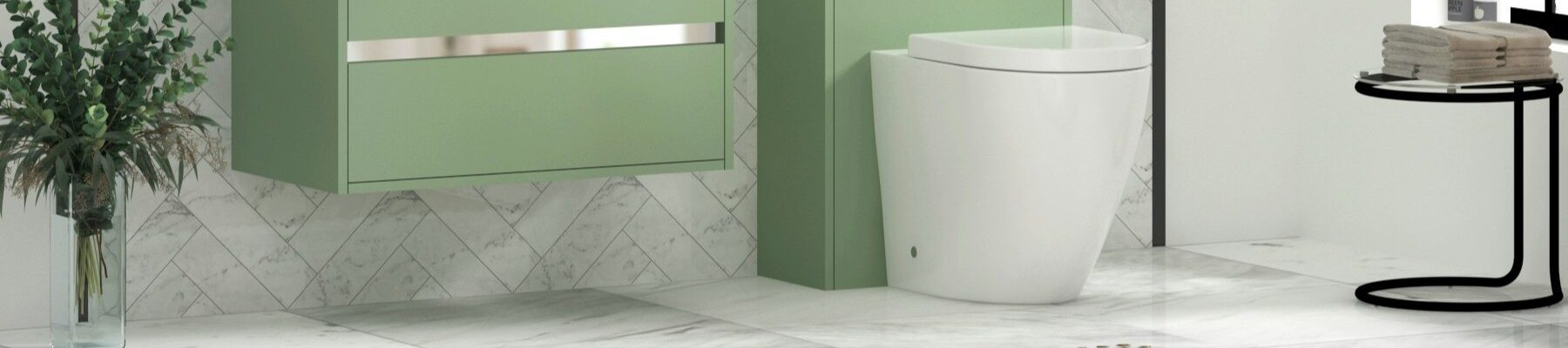 Modern bathroom featuring a wall-hung mint/sage green vanity unit with a white ceramic basin and chrome trim, paired with a matching back-to-wall toilet unit. The space is finished with white marble tiled walls in a herringbone pattern, light marble floor tiles, a brown bath mat, and decorative greenery in a clear vase.