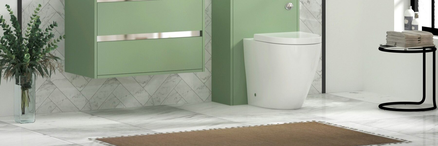Modern bathroom featuring a wall-hung mint/sage green vanity unit with a white ceramic basin and chrome trim, paired with a matching back-to-wall toilet unit. The space is finished with white marble tiled walls in a herringbone pattern, light marble floor tiles, a brown bath mat, and decorative greenery in a clear vase.