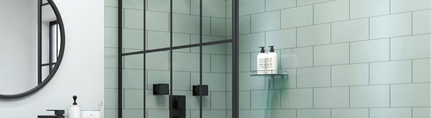A modern bathroom featuring a black grid wet room shower screen against sage green subway tiles, alongside a black rainfall shower head and matching fixtures.