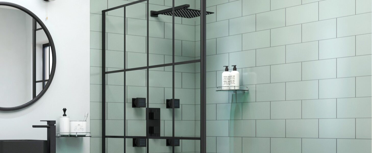 A modern bathroom featuring a black grid wet room shower screen against sage green subway tiles, alongside a black rainfall shower head and matching fixtures.